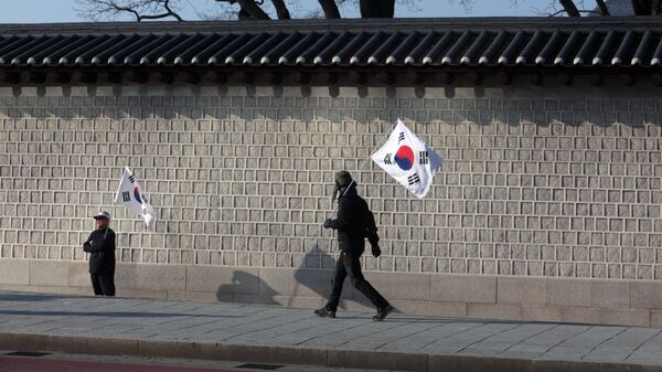 Мужчины с флагами Южной Кореи на одной из улиц в Сеуле