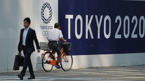 Пешеходы проходят мимо символики Олимпийских игр в Токио