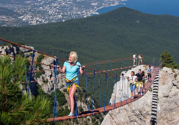 Туристы идут по веревочной лестнице между зубцами горы Ай-Петри в Крыму.