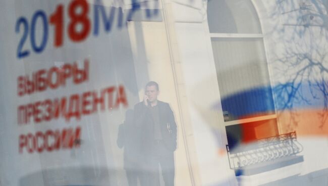 Отражение в окне баннера с информацией о выборах президента России. Архивное фото