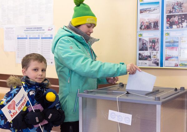 Женщина опускает бюллетень в урну на выборах президента РФ на избирательном участке №51 в Петропавловске-Камчатском.