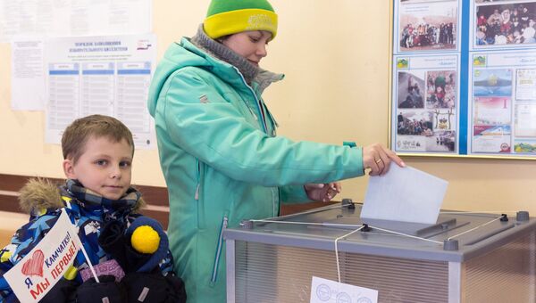 Женщина опускает бюллетень в урну на выборах президента РФ на избирательном участке №51 в Петропавловске-Камчатском.