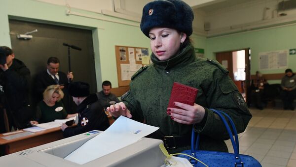 Женщина опускает бюллетень в урну на выборах президента РФ на избирательном участке №76 в Москве. 18 марта 2018