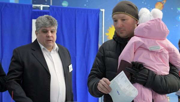 Мужчина с ребенком во время голосования на выборах президента РФ на избирательном участке № 90 в Москве. 18 марта 2018