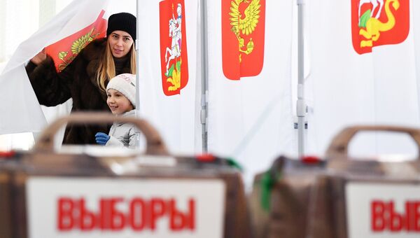 Женщина с ребенком во время голосования на выборах президента РФ на избирательном участке №13-06 в Москве. 18 марта 2018