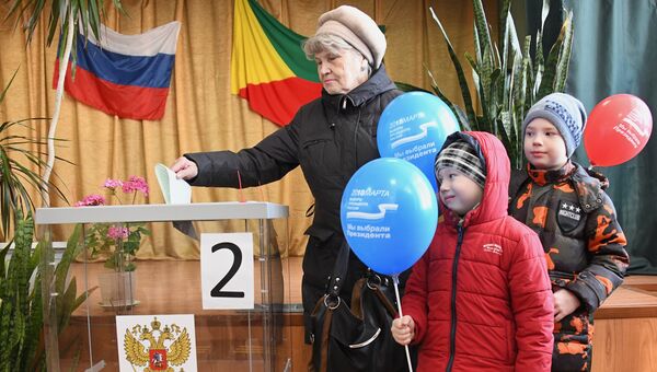 Женщина опускает бюллетень в урну на выборах президента Российской Федерации на избирательном участке в Чите. 18 марта 2018