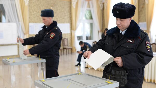 Сотрудники полиции опускают бюллетени в урны на выборах президента РФ на избирательном участке в Бахчисарае. 18 марта 2018