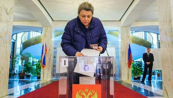 Женщина опускает бюллетень в урну на выборах президента РФ на избирательном участке в посольстве Российской Федерации в Вашингтоне. 18 марта 2018