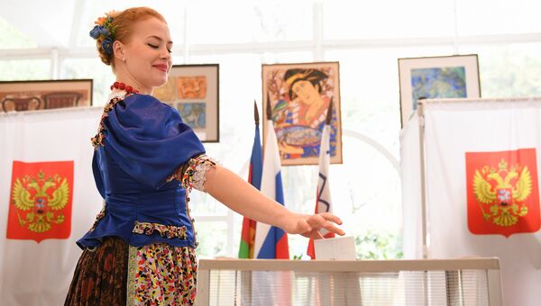 Девушка в национальном костюме голосует на выборах президента РФ в Сочи