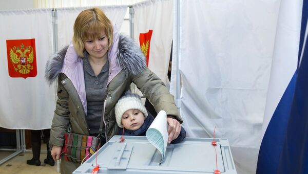 Женщина с ребенком голосует на выборах президента РФ на избирательном участке в Российском центре науки и культуры Кишинева, Молдавия. 18 марта 2018