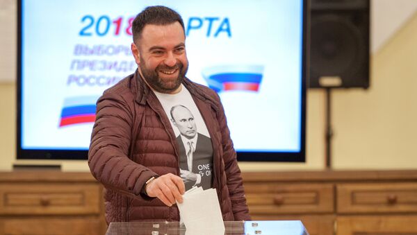 Мужчина опускает бюллетень в урну во время голосования на выборах президента Российской Федерации