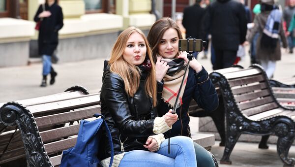 Девушки фотографируются на Никольской улице в Москве.