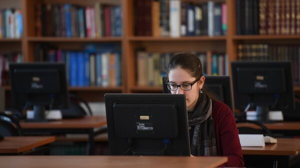 Девушка сидит за компьютером в библиотеке