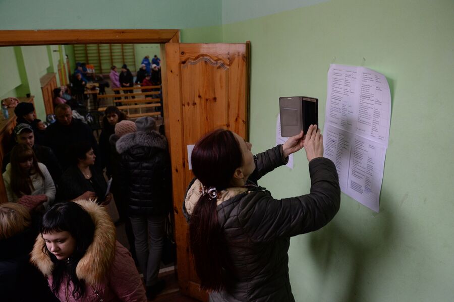 Женщина фотографирует на мобильный телефон списки пропавших без вести при пожаре в торговом центре Зимняя вишня в Кемерово