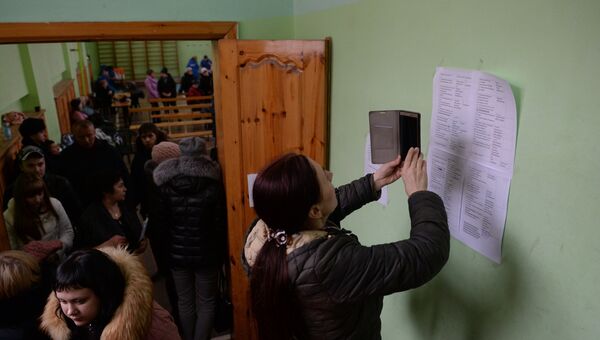 Женщина фотографирует на мобильный телефон списки пропавших без вести при пожаре в торговом центре «Зимняя вишня» в Кемерово