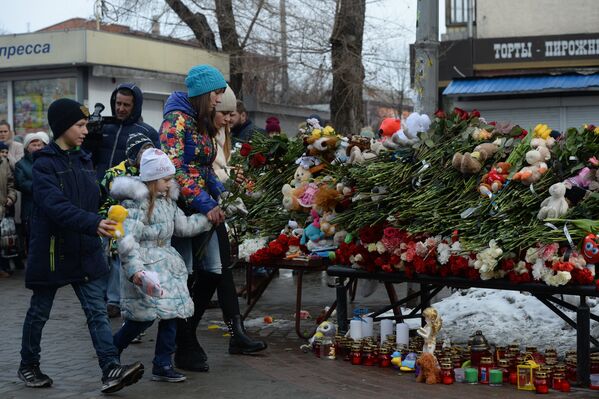 Жители несут цветы и мягкие игрушки к зданию торгового центра «Зимняя вишня» в Кемерово, где произошел пожар