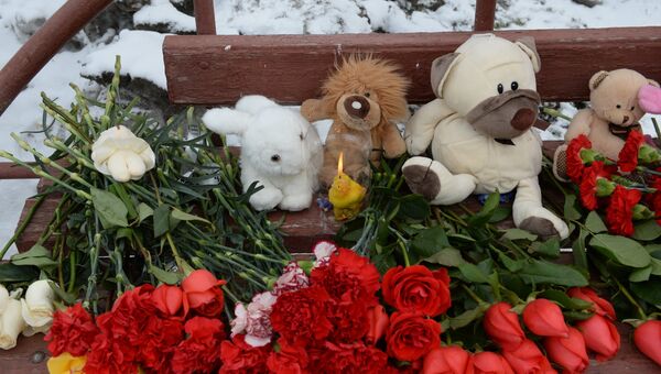 Цветы, свечи и мягкие игрушки возле здания торгового центра «Зимняя вишня» в Кемерово, где произошел пожар
