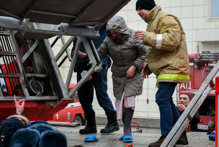 Сотрудники пожарной охраны МЧС помогают посетителям выбраться из торгового центра Зимняя вишня в Кемерово, где произошел пожар Сотрудники пожарной охраны МЧС помогают посетителям выбраться из торгового центра Зимняя вишня в Кемерово, где произошел пожар