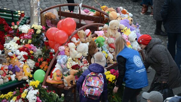 Цветы и мягкие игрушки возле здания торгового центра Зимняя вишня в Кемерово, где произошел пожар