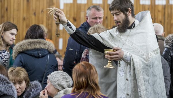 Священник проводит обряд с родственниками подстардаших при пожаре в ТЦ Зимняя вишня в Кемерово. 26 марта 2018