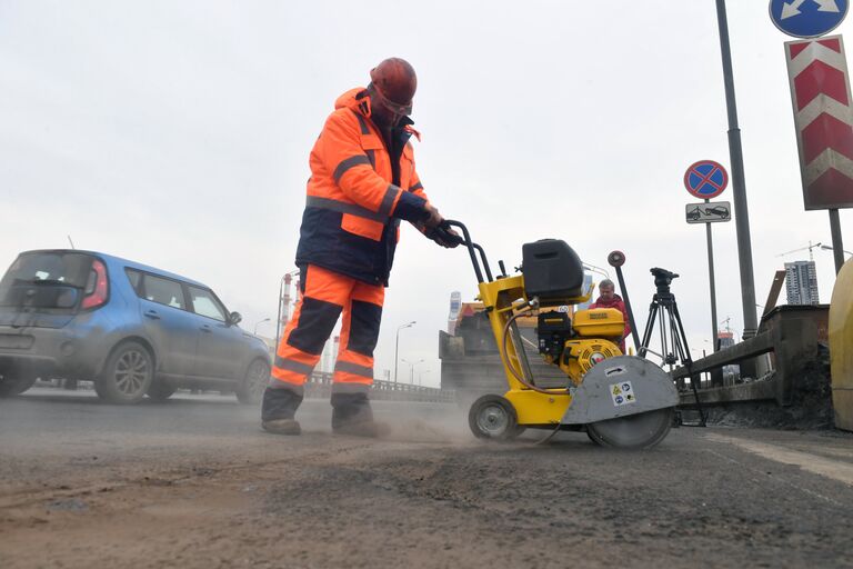 Рабочие ремонтируют участок дороги в Москве