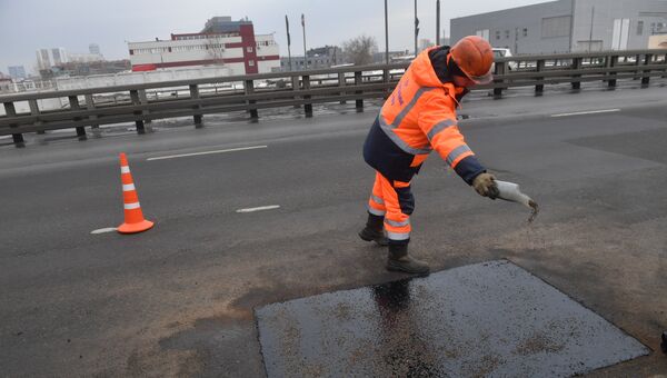 Рабочие ремонтируют участок дороги