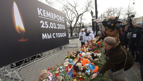 Люди возлагают цветы к мемориалу на Манежной площади в Москве в память о погибших в кемеровском торговом центре Зимняя вишня