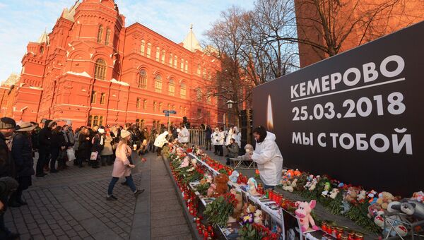 Люди возлагают цветы к мемориалу на Манежной площади в Москве в память о погибших в кемеровском торговом центре Зимняя вишня