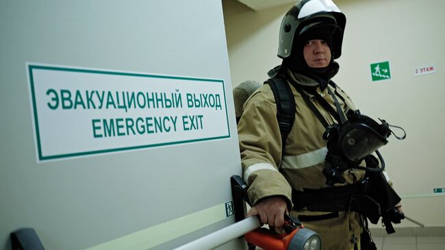 Сотрудник противопожарной службы у эвакуационного выхода во время учений в торговом центре. Архивное фото