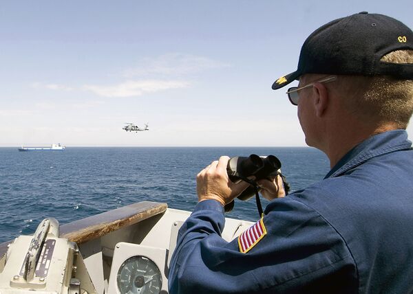 Сотрудник военно-морской службы США наблюдает за судном Фаина