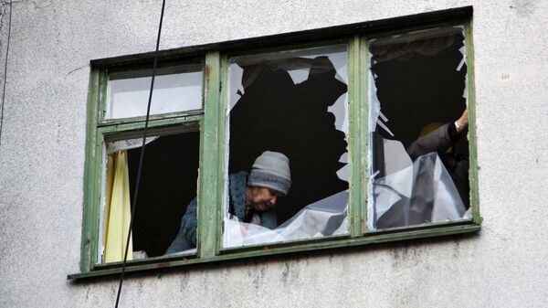 Женщина у окна жилого дома в центре города Ясиноватая, пострадавшего в результате обстрела. Архивное фото