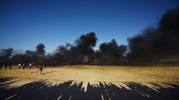 Палестинские протестующие во время столкновений с израильскими военными на границе сектора Газа и Израиля.