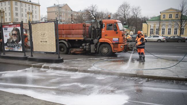 Сотрудник коммунальных служб моет тротуар шампунем в Москве