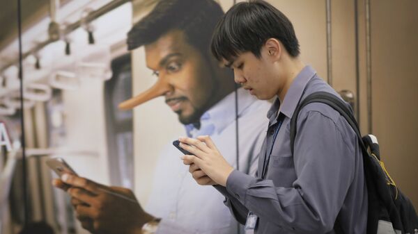 Молодой человек проходит мимо рекламы, запрещающей распространение фейковых новостей на вокзале в Куала-Лумпур, Малайзия 