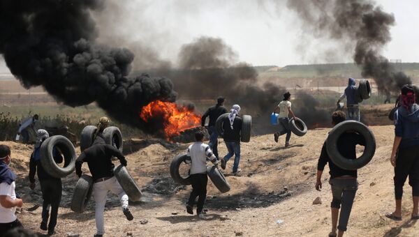 Палестинские протестующие во время столкновений с израильскими военными на границе сектора Газа и Израиля. 6 апреля 2018