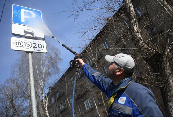 Сотрудник коммунальной службы моет дорожный знак в Юго-Восточном административном округе города Москвы