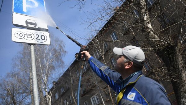 Сотрудник коммунальной службы моет дорожный знак в Юго-Восточном административном округе города Москвы