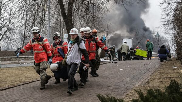 Сторонники оппозиции несут раненного за баррикады на площади Независимости в Киеве