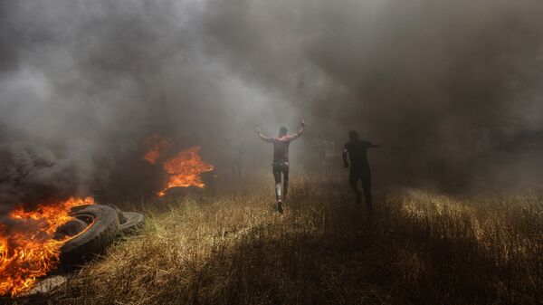 Палестинские протестующие во время столкновений с израильскими военными на границе сектора Газа и Израиля