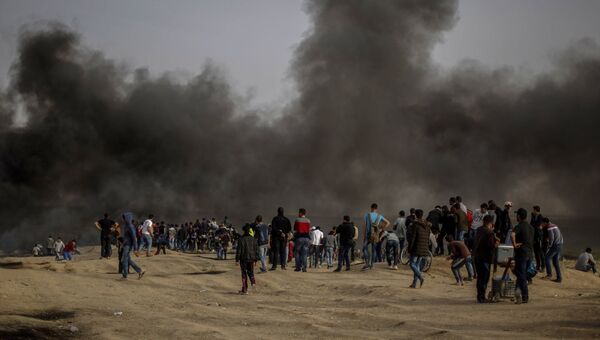 Палестинские протестующие во время столкновений с израильскими военными на границе сектора Газа и Израиля