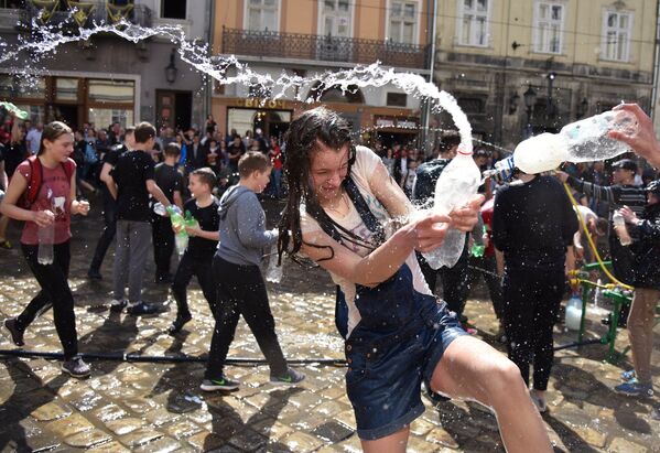Участники во время праздничных обливаний водой на площади Рынок во Львове
