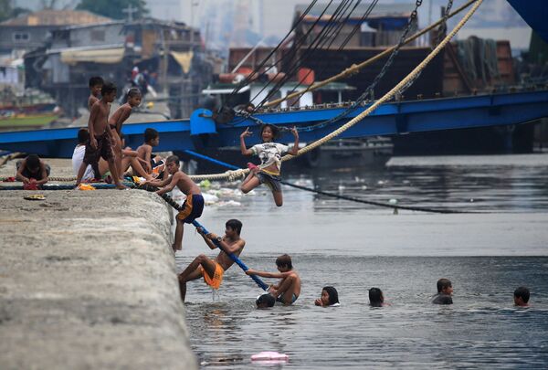 Дети купаются в Манильском заливе во время жаркой погоды на Филиппинах