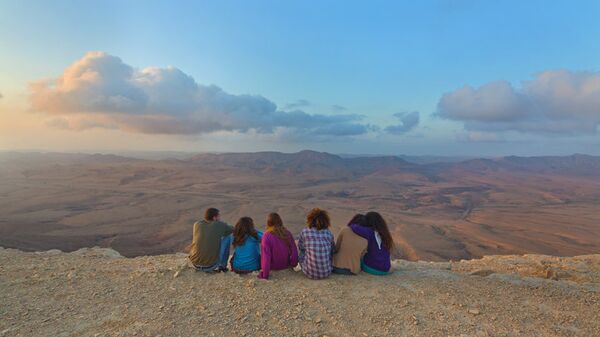 Туристы на краю кратера Рамон в пустыне Негев на рассвете
