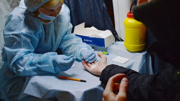 Медицинский работник производит экспресс-анализ крови в мобильном пункте. Архивное фото