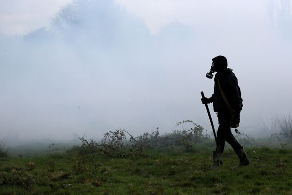 Протестующий в облаке слезоточивого газа во время столкновений с французскими жандармами в Нотр-Дам-де-Ланде, Франция