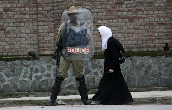 Мусульманская студентка проходит мимо полицейского во время протеста против изнасилования в городе Сринагар, Индия