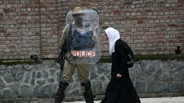 Мусульманская студентка проходит мимо полицейского во время протеста против изнасилования в городе Сринагар, Индия 