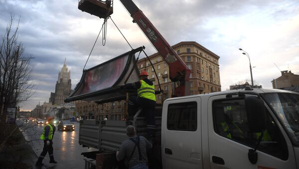 Рабочие грузят рекламный щит, поваленный ураганным ветром на углу Смоленского бульвара и 1-ого Неопалимовского переулка в Москве. 21 апреля 2018