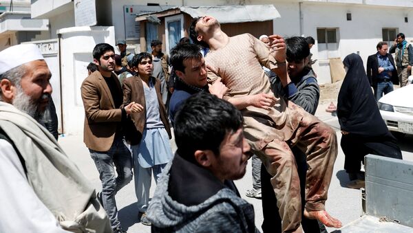 Люди переносят жертв раненых во время подрыва террориста-смертника в Кабуле, Афганистан. 22 апреля 2018