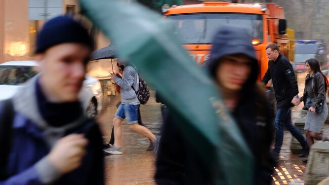 Пешеходы на улице в Москве во время сильного дождя